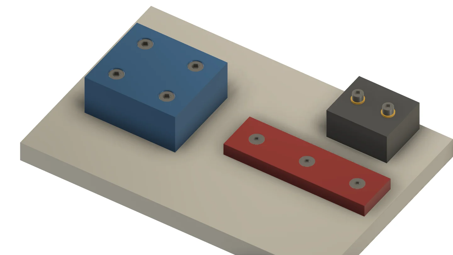Fixture plate with a blue locating block on counterbored M8 screws, a red clamp bar on flush countersunk M6 screws and a stop block on M6 screws with washers